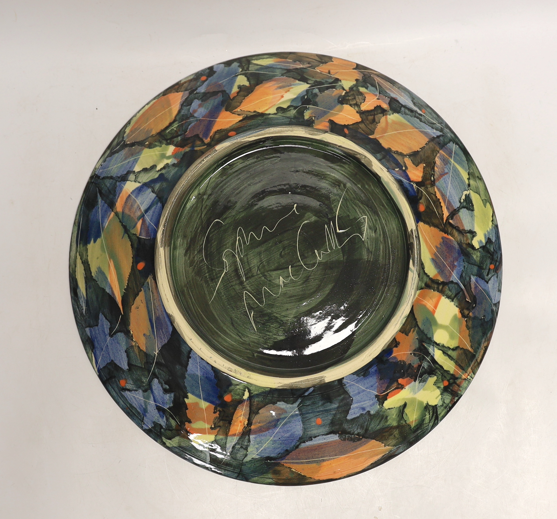 A large studio pottery plate by Sophie McCarthy, decorated with a variety of autumnal leaves, signed to the base, 39.5cm